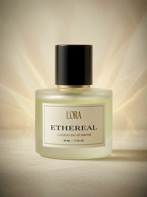 ETHEREAL Layering Eau de Parfum by L'ORA — frosted glass bottle with black cap in radiant golden light
